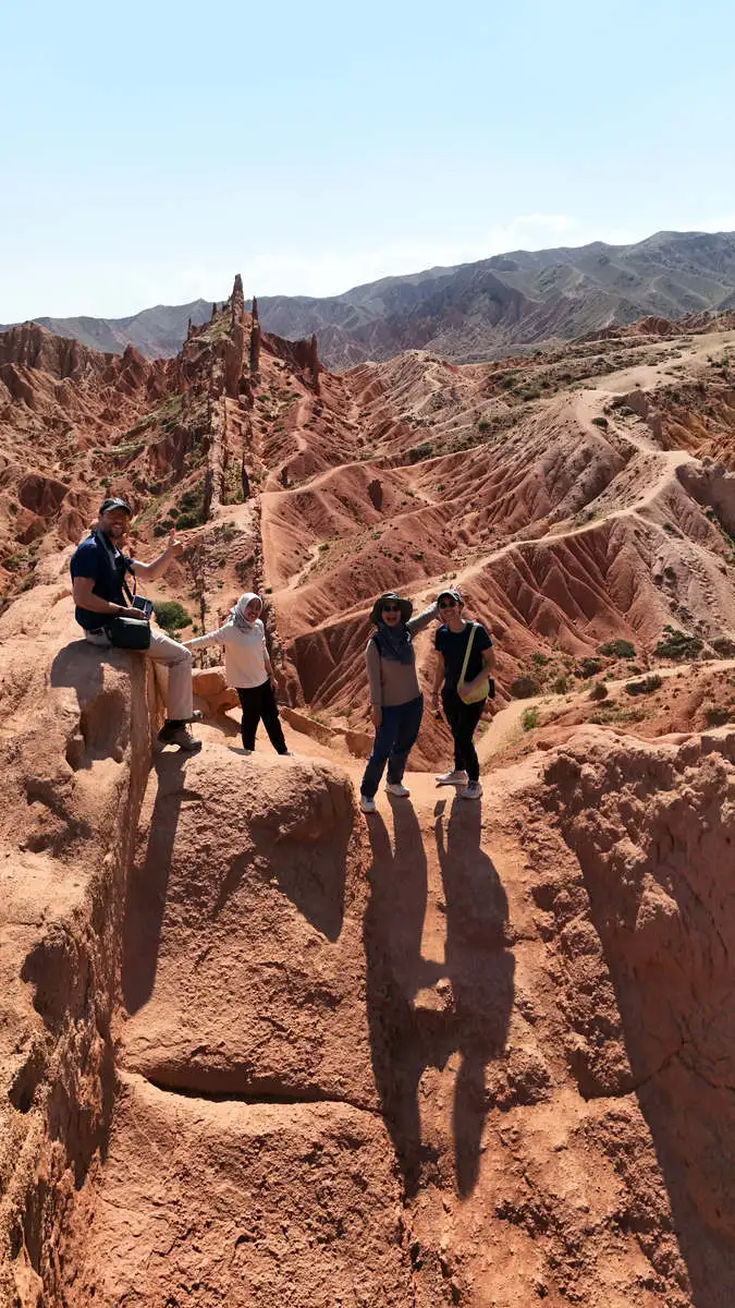 Group of tourists posing on a rock ledge overlooking Fairytale Canyon's spires